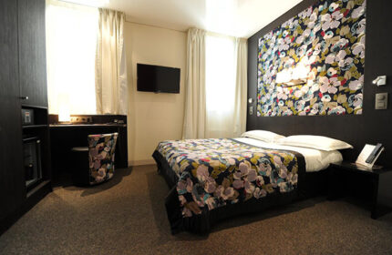 Hotel Du Vieux Saule room. Chic, cool design in this gay hotel in Paris city center. Floral bedspread and headboard, desk, TV.
