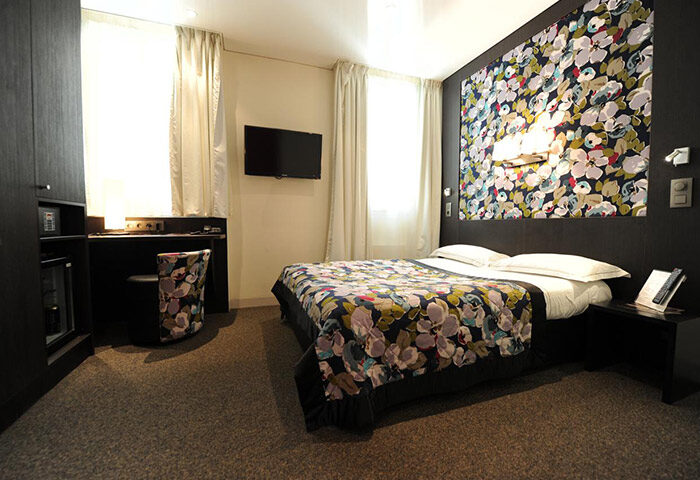 Hotel Du Vieux Saule room. Chic, cool design in this gay hotel in Paris city center. Floral bedspread and headboard, desk, TV.