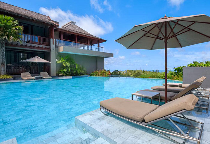 Avista Hideaway Phuket Patong MGallery rooftop pool. Chic luxury gay hotels in Phuket. Loungers, umbrella, blue sky. Gay travel.
