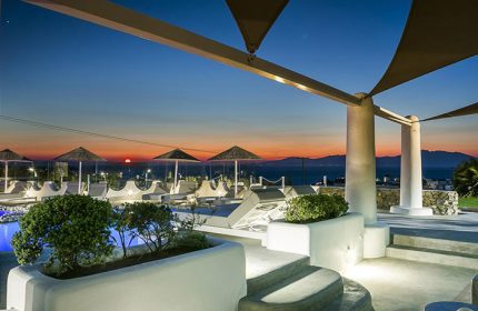 Ilio Maris gay hotel in Mykonos. Chic design, upscale honeymoon destination. Sunset view from the pool area, lounge chairs, and parasols.