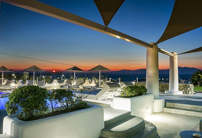 Ilio Maris gay hotel in Mykonos. Chic design, upscale honeymoon destination. Sunset view from the pool area, lounge chairs, and parasols.