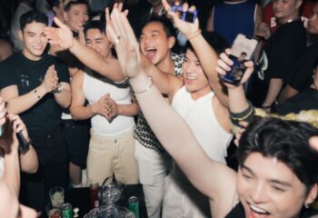 Gay nightlife: jubilant crowd cheers at Chin Chin Bar, a popular gay bar in Ho Chi Minh City, Vietnam. Men raise arms in celebration.