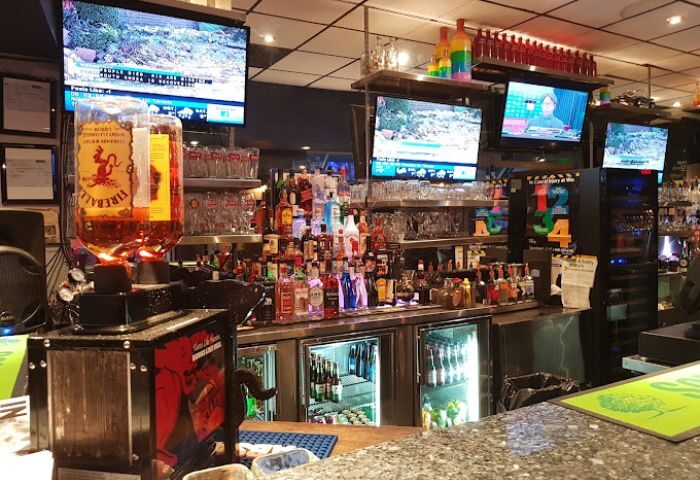 Church Street Garage Resto-Bar in Toronto: Bar interior with liquor bottles, glasses, and TVs. A gay-friendly travel destination.