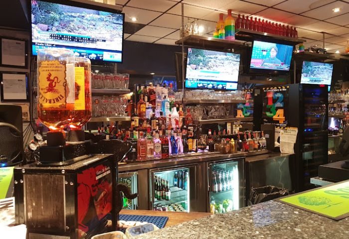 Church Street Garage Resto-Bar in Toronto: Bar interior with liquor bottles, glasses, and TVs. A gay-friendly travel destination.