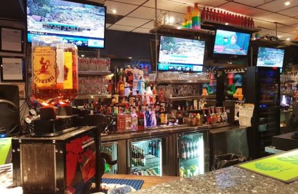 Church Street Garage Resto-Bar in Toronto: Bar interior with liquor bottles, glasses, and TVs. A gay-friendly travel destination.
