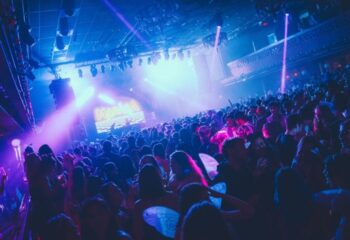 Packed dance floor at Churros con Chocolate gay club in Barcelona, Spain. Blue and purple lights illuminate the crowd.