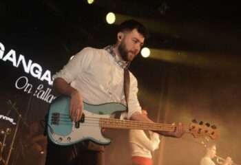 Live music at Churros con Chocolate, a gay club in Barcelona. A bearded man plays bass guitar on stage with other musicians.