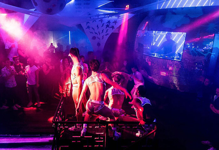 CIRCA The Club, Embankment, London. Go-go boys dance in a late-night gay club with colorful lights and a DJ. Best gay dance club in London.