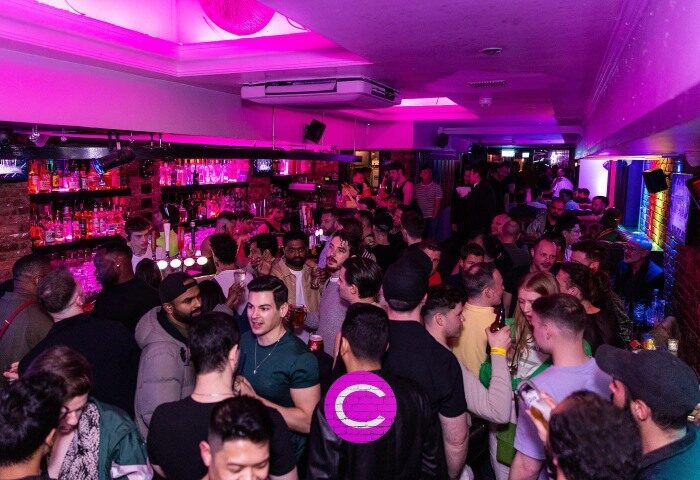 Crowded CIRCA Soho gay bar in London. The hottest crowd enjoys drinks under purple lights. Popular gay bar destination for gay men travelers.