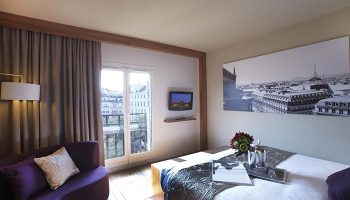 Citadines Les Halles Paris room. Modern gay-friendly hotel in Marais gayborhood. Comfy bed, purple couch, Paris view. Most booked hotel.
