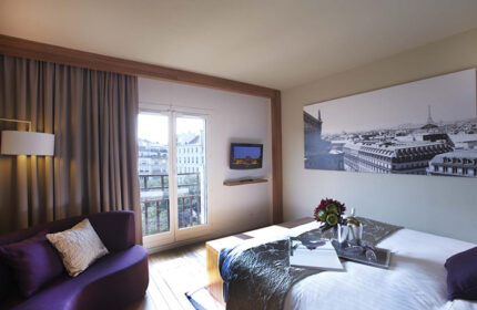 Citadines Les Halles Paris room. Modern gay-friendly hotel in Marais gayborhood. Comfy bed, purple couch, Paris view. Most booked hotel.