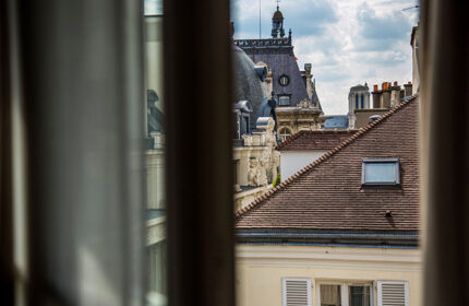 View from Duo Hotel, a city-center hotel idea in Paris' Gayborhood. Rooftops and architecture seen through a window. Gay travel.