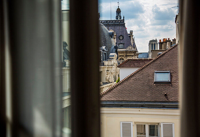 View from Duo Hotel, a city-center hotel idea in Paris' Gayborhood. Rooftops and architecture seen through a window. Gay travel.