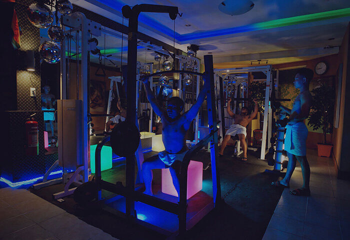 Gym at Club Bath Sauna Manila, a top gay sauna and cruising place. Men work out in a neon-lit space with disco balls. Gay travel advice.