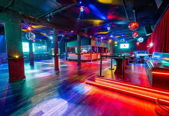 Club Cobra dancefloor. Gay club interior with disco balls, colorful lights, bar, and seating. Nightlife destination for gay men's travel.