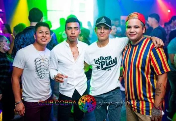 Gay Club Cobra night out: Four men pose at the gay nightclub. Nightlife scene with colorful lights. Gay travel advice.