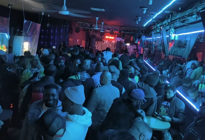 Inside Escape Club in Chicago, a crowded party scene with drag shows, neon lights, and a diverse crowd enjoying the nightlife.
