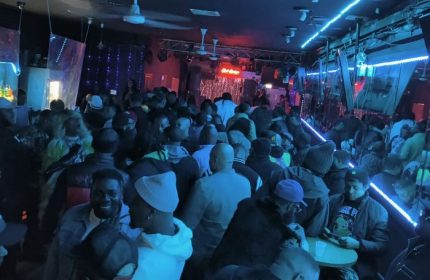 Inside Escape Club in Chicago, a crowded party scene with drag shows, neon lights, and a diverse crowd enjoying the nightlife.