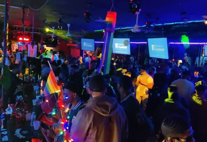 Crowded Chicago gay club party. Rainbow flags, colorful lights, and Facebook signs. Escape Drag Shows event. Gay men travel.