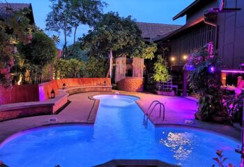 Club One Seven, gay men's hotel in Chiang Mai. Pool area at night, illuminated with purple and orange lights. Sauna and travel destination.