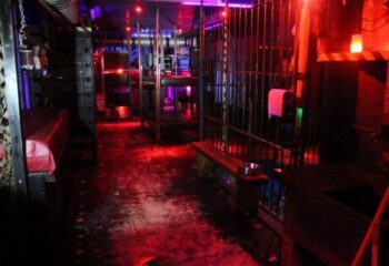 Inside Open Mind Gay Cruise Club in Barcelona. Dark, with cages, beds, and red lighting, creating an intimate atmosphere for gay men's travel.