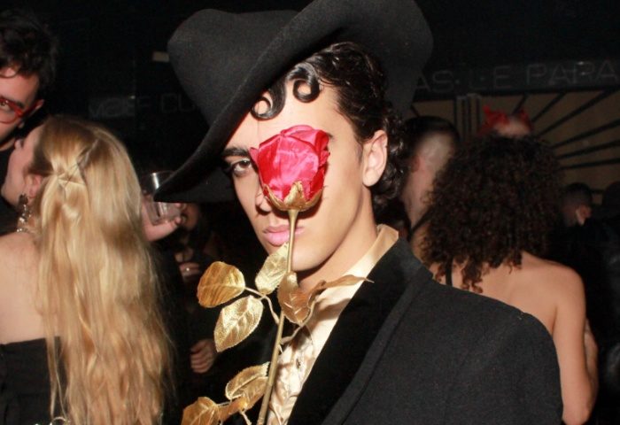 Man with hat & rose at Club Plastic Milano. Gay nightlife travel. Milan's vibrant gay scene. Stylish clubbing experience.