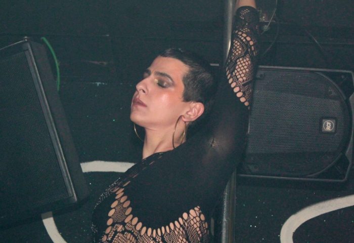 Drag queen at Club Plastic Milano, a gay-friendly nightclub. Person in black lace top with gold hoop earrings and short dark hair.