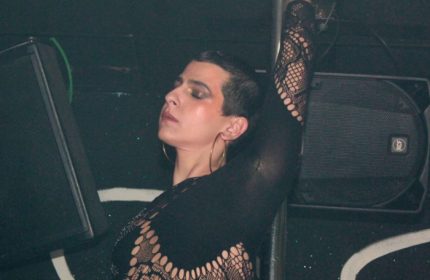 Drag queen at Club Plastic Milano, a gay-friendly nightclub. Person in black lace top with gold hoop earrings and short dark hair.