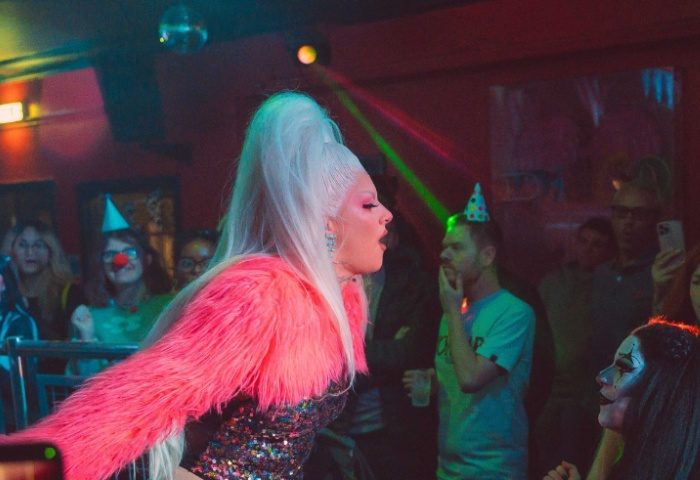 Drag queen performance at Club Tropicana Manchester. Gay nightlife scene with partygoers and vibrant atmosphere. LGBTQ+ travel.