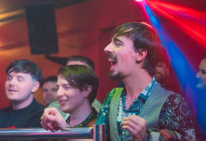 Gay men enjoying the Club Tropicana Manchester nightlife. The club is lit with red and blue lights, creating a vibrant atmosphere.