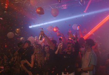 Montreal gay party at Club Unity. People celebrate with champagne, balloons, and confetti. Nightlife scene with laser lights. Gay travel advice.
