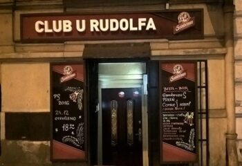 Entrance to Club U Rudolfa, a gay-friendly bar in Prague. Signage for Gambrinus beer. Menu boards list drinks. Gay travel advice.