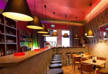 Clubsauna Amsterdam interior. Bar, tables, and chairs under warm lighting. Gay sauna Frankfurt's lounge area, inviting for relaxation.
