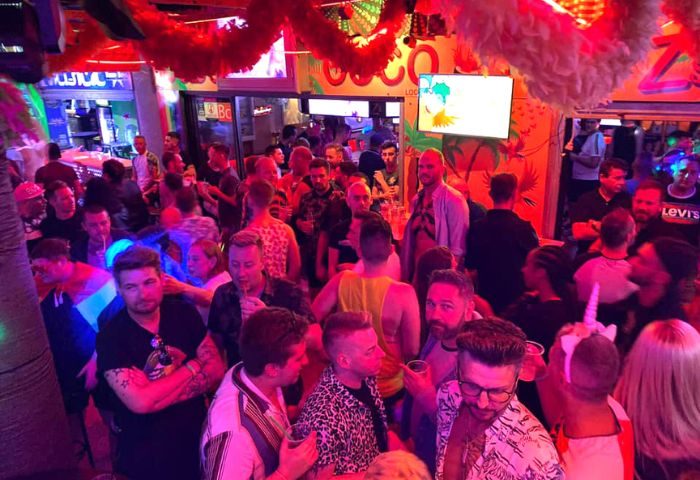 Coco Loco Gay Bar in Gran Canaria: A lively, crowded scene at a popular gay bar. Men are socializing and drinking. Nightlife.