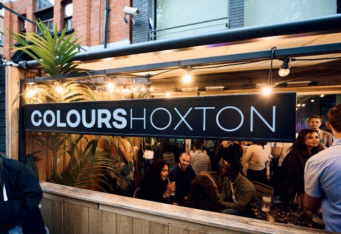 Colours Hoxton, coolest gay bar in London. Outdoor seating area with people enjoying drinks. Gay travel advice for Hoxton, London.