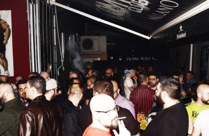 Crowded Company Club Milano gay bar scene. Men socializing, smoking, and drinking. Gay nightlife travel advice.