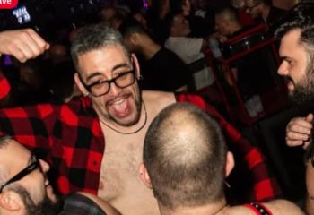 Gay nightlife in Rome: Man in red plaid shirt at a crowded gay bar. Gay travel advice for Rome, Italy. Company Roma Rome.