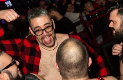 Gay nightlife in Rome: Man in red plaid shirt at a crowded gay bar. Gay travel advice for Rome, Italy. Company Roma Rome.