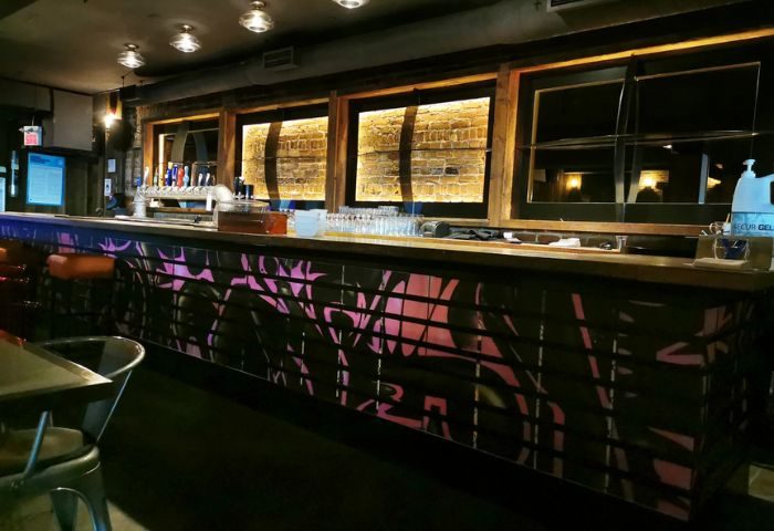 Sky Complex bar interior in Montreal's Gay Village. The bar is decorated with pink graffiti and brickwork. Gay travel advice.