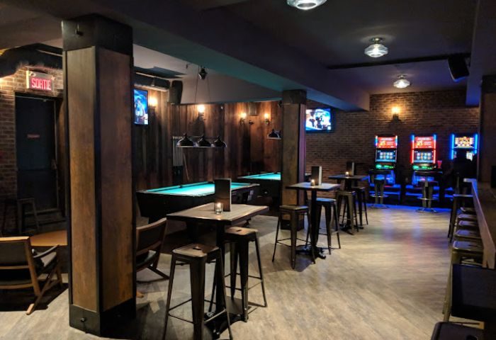 Sky Complex gay bar in Montreal. Pool tables, slot machines, and bar seating in a dimly lit, modern space. Gay travel advice.