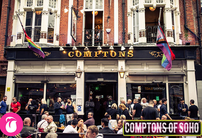 Comptons of Soho, a popular gay bar in London's Old Compton Street. Crowds mingle outside, flags fly, marking it as a top gay travel destination.