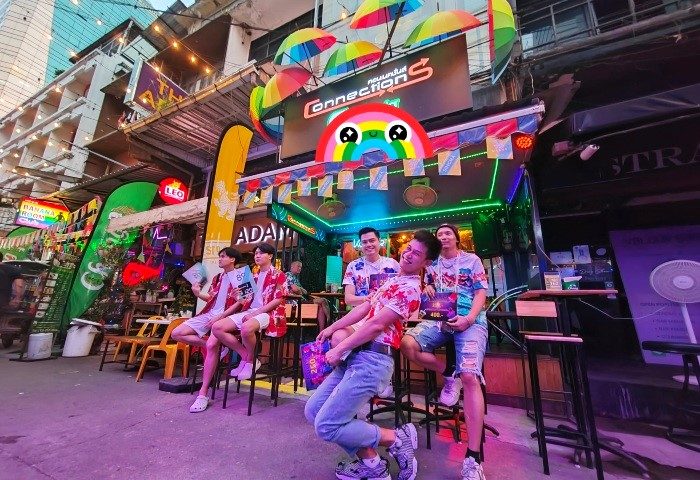 Bangkok's Connection Bar: a vibrant gay bar for people-watching. Rainbow umbrellas decorate the entrance. Men hang out in front.
