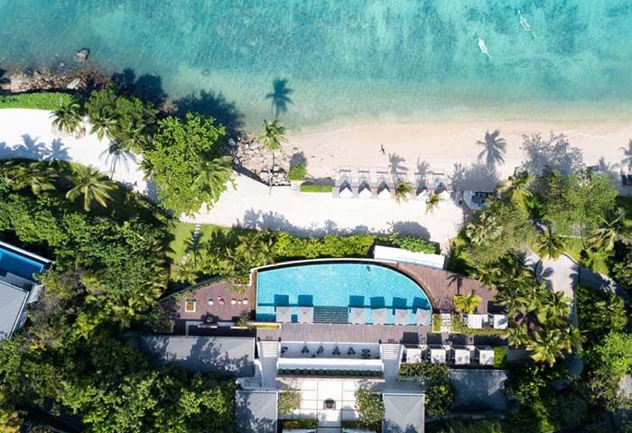 Aerial view of Conrad Koh Samui, an LGBT-friendly resort. Pool, beach, and lush greenery create a tropical paradise for gay travelers.