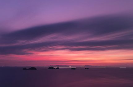 Sunset view from Conrad Koh Samui, LGBT-friendly resort. Pink and purple sky over the ocean with small islands. Gay travel in Thailand.