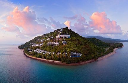 Conrad Koh Samui aerial view. Villas dot a lush, tropical hillside meeting turquoise waters. A gay travel paradise in Thailand.