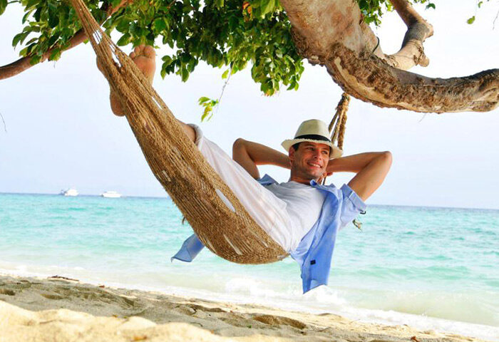 Phi Phi Holiday Resort: Gay man relaxing in a hammock on a cool beachfront at Koh Phi Phi. Tropical beach vacation lifestyle.