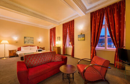 Hotel Leonardo Prague suite. Cool design gay hotel in Prague Old Town city center. Red sofa, chair, bed, & curtains.