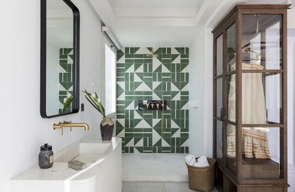 Upscale Porto Mykonos Hotel bathroom. Cool design with green geometric tiles, stone sink, and glass wardrobe. Gay hotel in Mykonos Town.