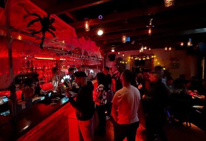 The Yard Bar, a cool gay bar in London's Soho. Halloween decorations, spider webs, and a lively crowd of people at the bar.
