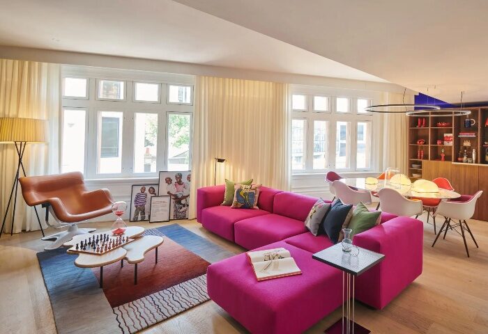 Andaz London Liverpool Street hotel room. Gay honeymoon suite, Shoreditch. Pink sofa, modern design, light wood floors, and large windows.